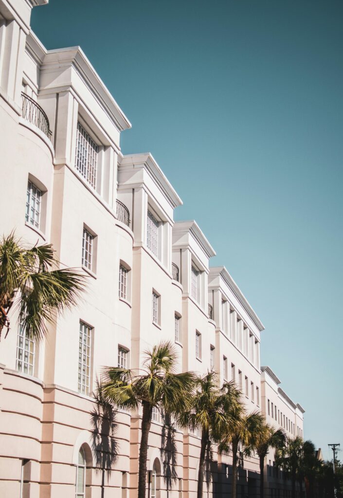 pexels-photo-1838640-1838640 Bright modern building facade with palm trees against a clear blue sky.