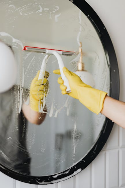 pexels-photo-4239139-4239139 Person cleaning a bathroom mirror using a squeegee for shiny, clear results.