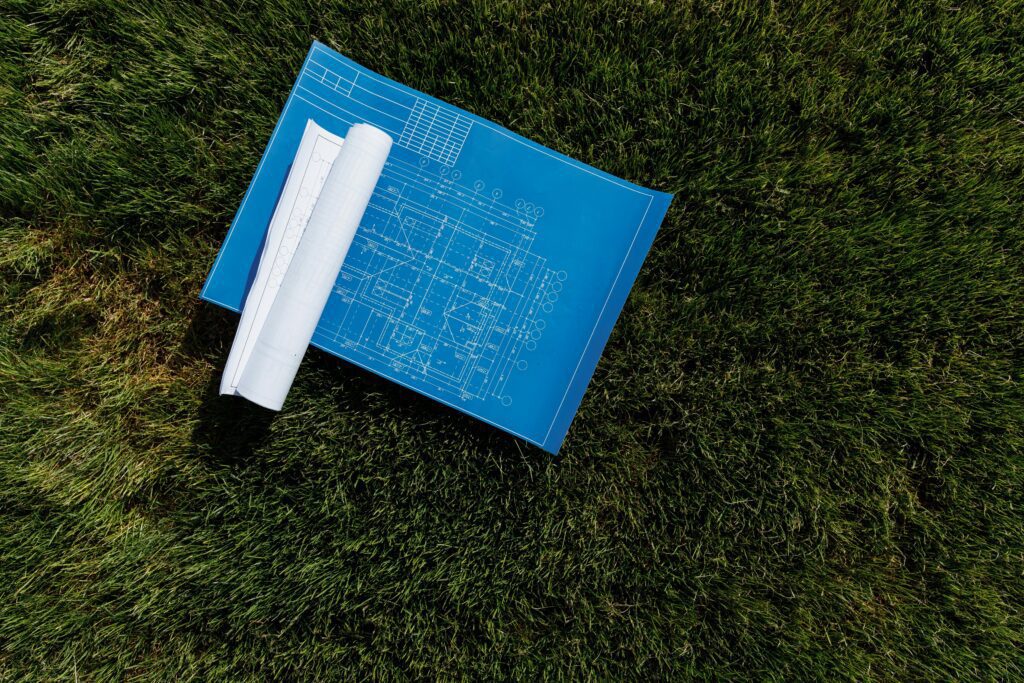 Top view of architectural blueprints on a grassy field, ideal for construction themes.